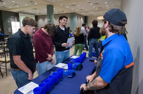 Students and Bluebonnet Ford staff smiling at a tech scholarship info booth