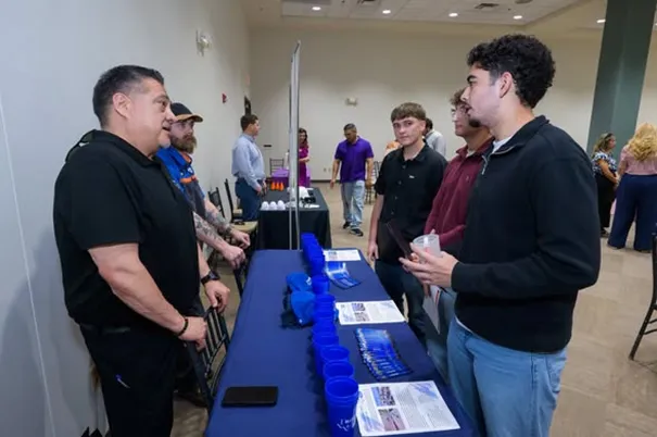 Students and Bluebonnet Ford staff in conversation at a tech scholarship info booth
